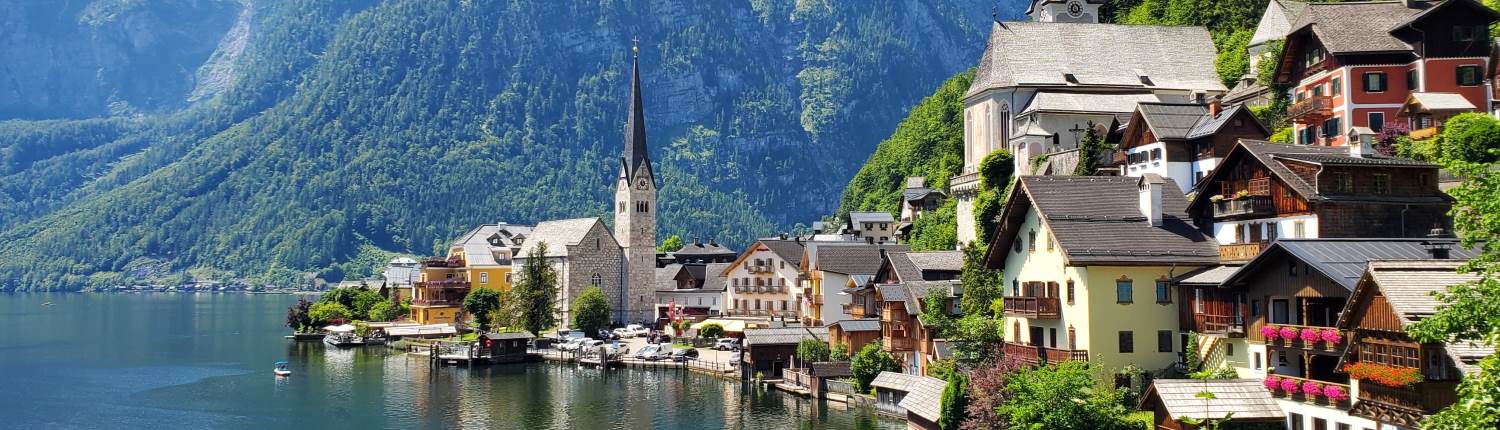 A lakeside church and traditional houses with mountains in the background in Hallstatt, Austria